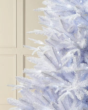 Close-up of 7ft pre-lit white pine tree with bright white lighting in front of white panelling 