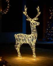 Pre lit warm white outdoor Stag silhouette on a snowy garden with a decorated Christmas tree in background
