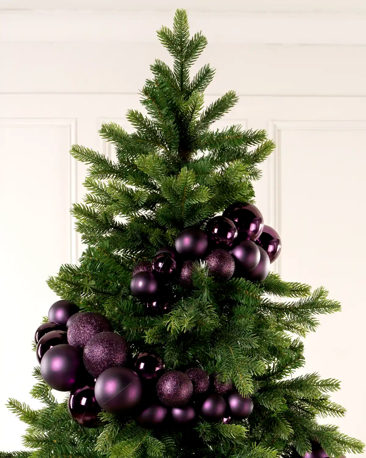 Purple Bauble Cluster Arch wrapped around a Christmas tree, showing clusters of purple baubles in different sizes and finishes