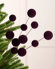 Purple bauble pick on a Christmas tree against a cream background