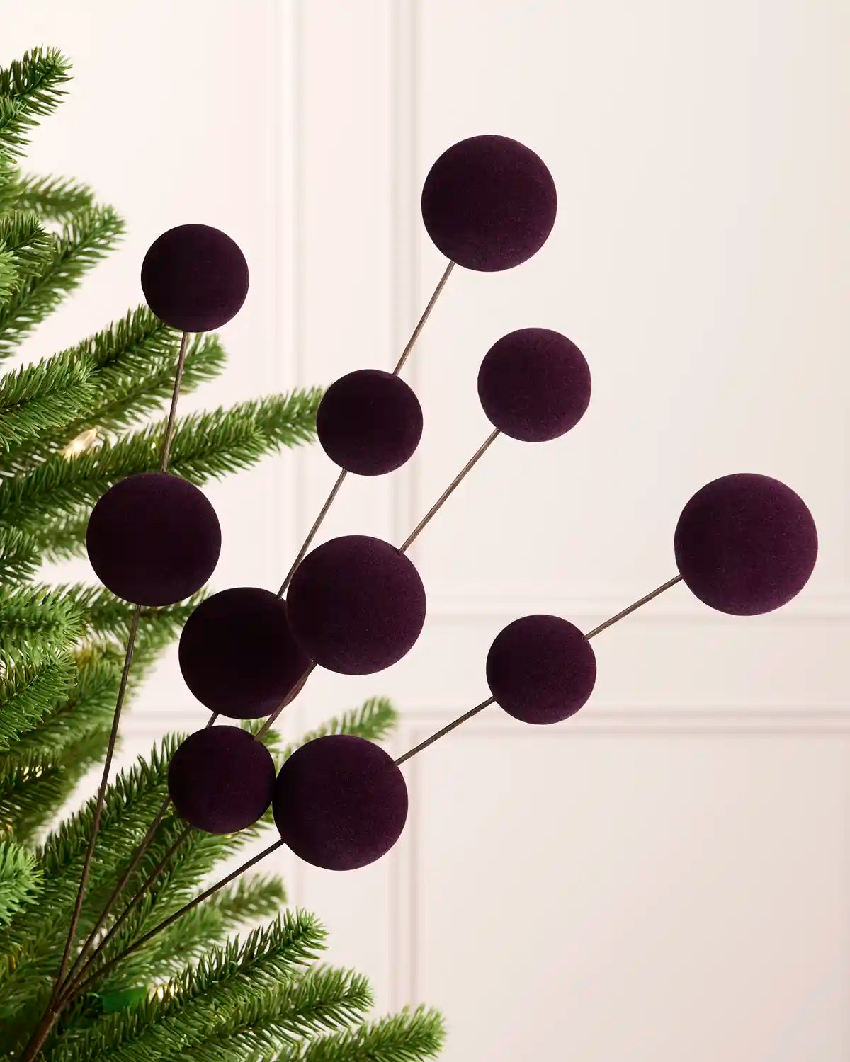 Purple bauble pick on a Christmas tree against a cream background