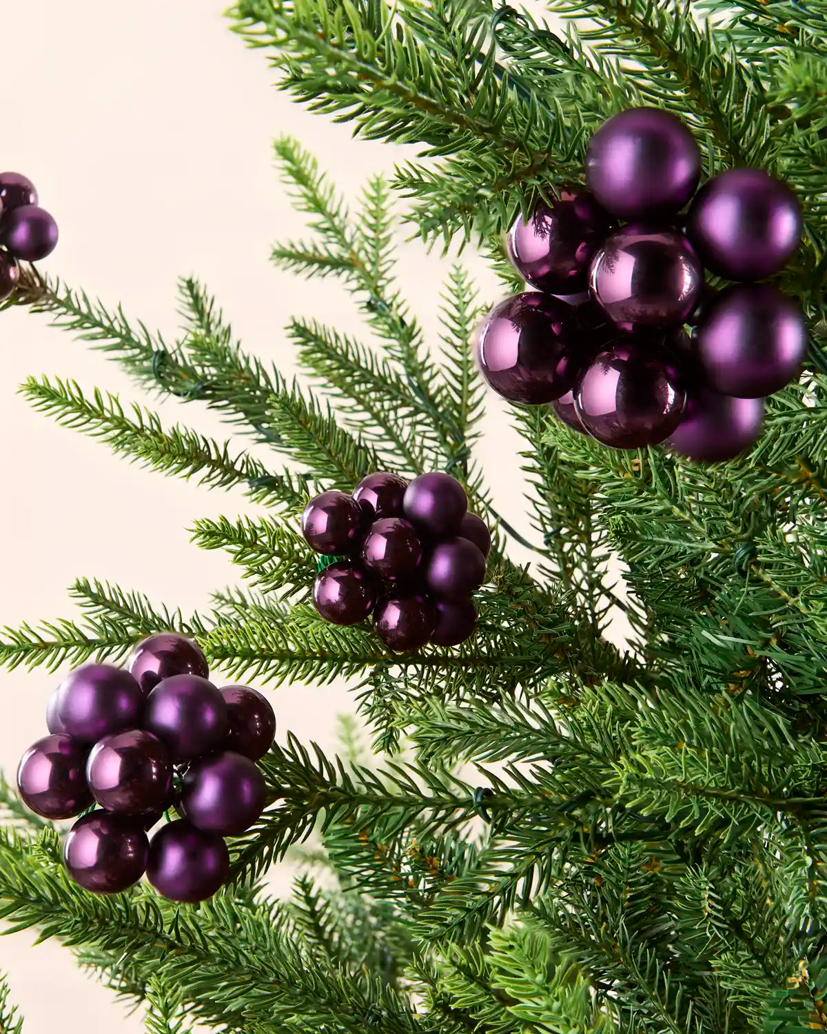 Purple berry cluster baubles with mixed shiny and matt glass finishes displayed on Christmas branches.
