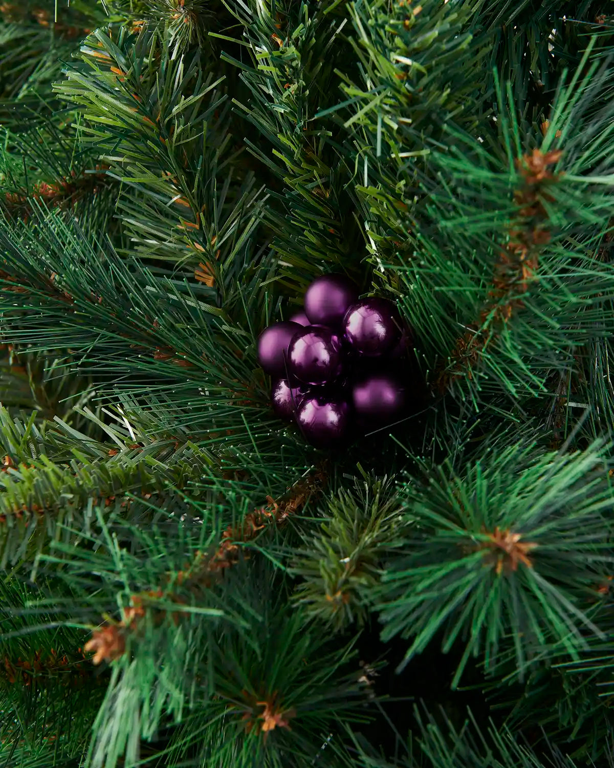 Purple glass berry cluster bauble placed in Christmas tree branches