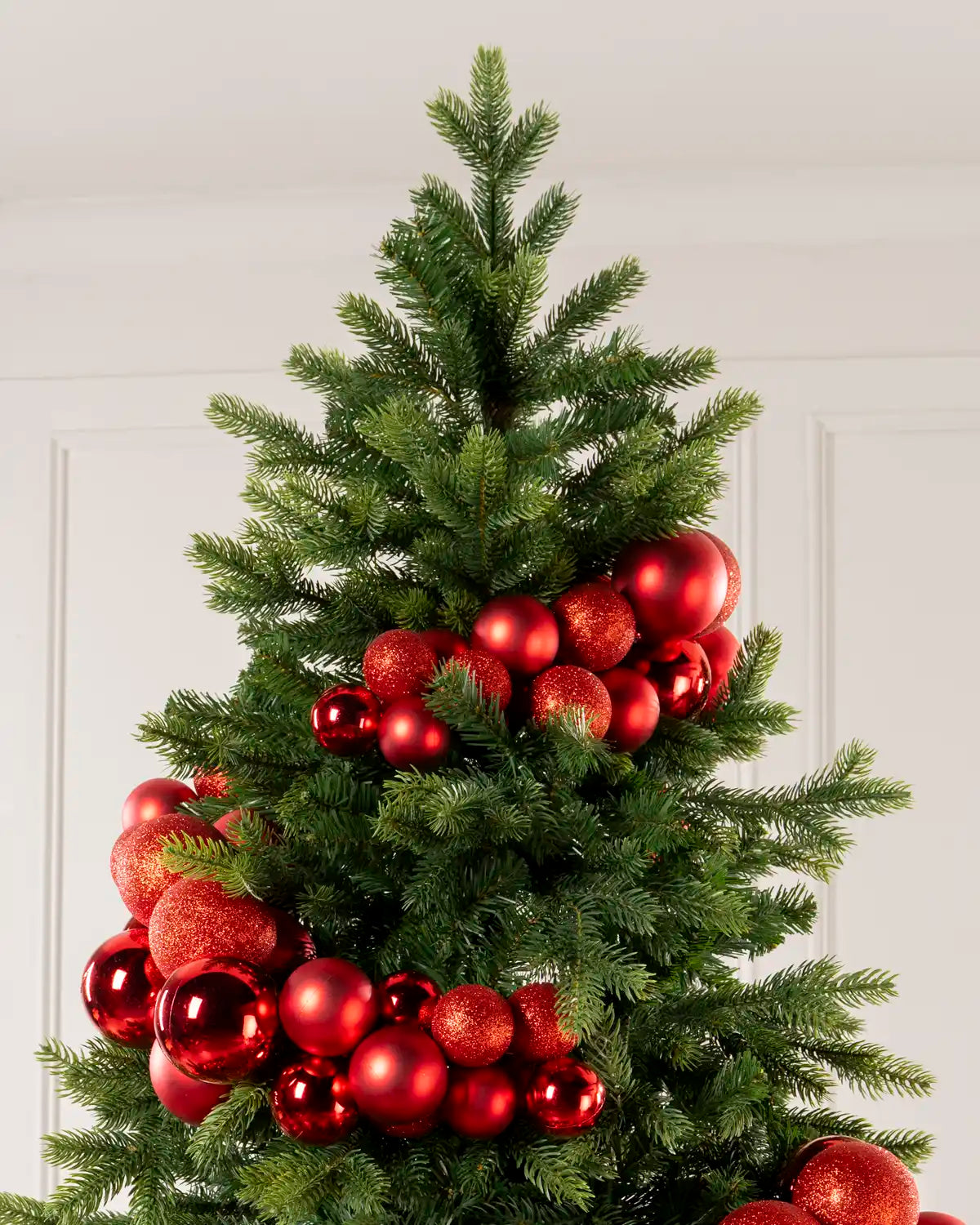 Red Bauble Cluster Arch wrapped around a Christmas tree, showing clusters of red baubles in different sizes and finishes