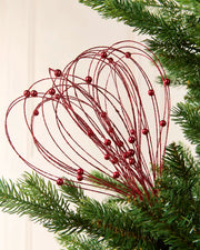 Red Glitter Nest Christmas Tree Pick placed in green Christmas tree branches with a cream background