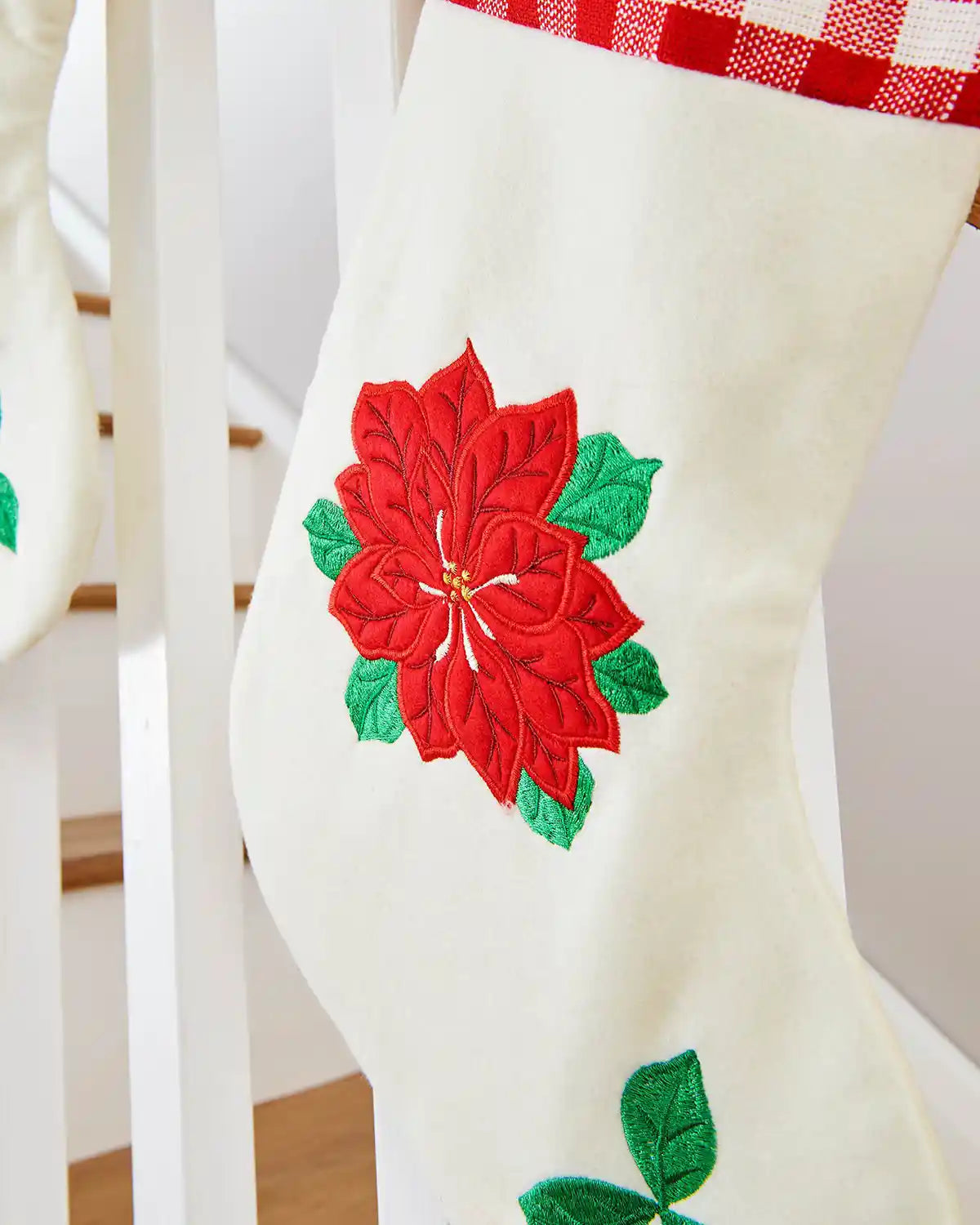 Close up White stocking with red poinsettia flower design on a white background on Staircase banister.