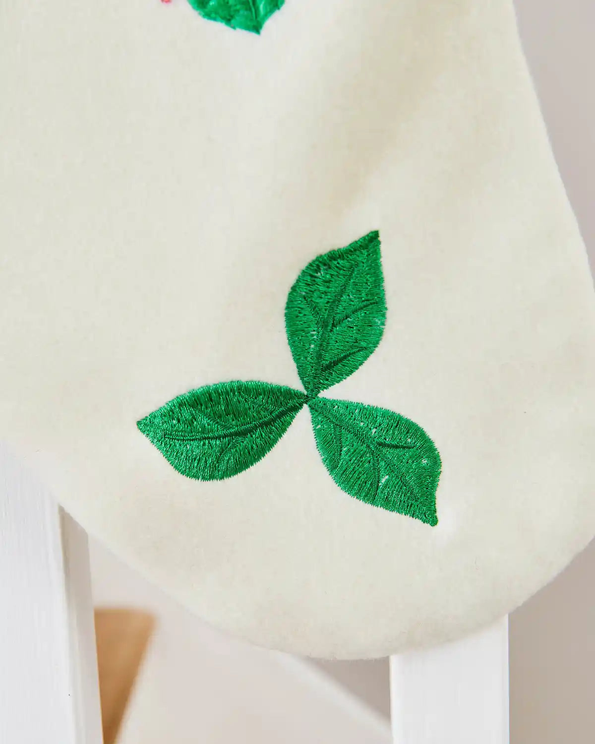 Close up of White Christmas Stocking with green leaf design at bottom. 