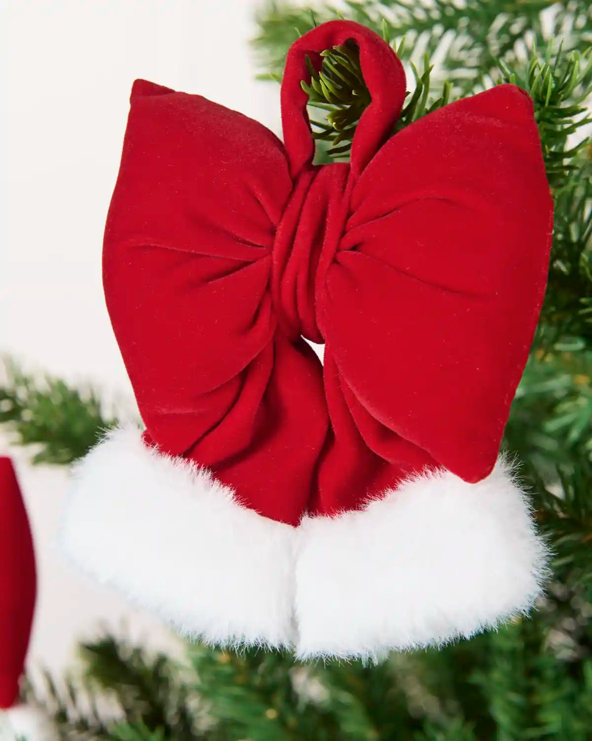 Red and White Mini Velvet Santa Bow hanging from Christmas tree branch
