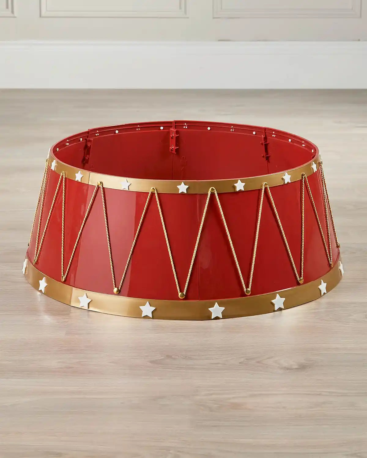 Red and gold decorative object with star patterns on a wooden floor.