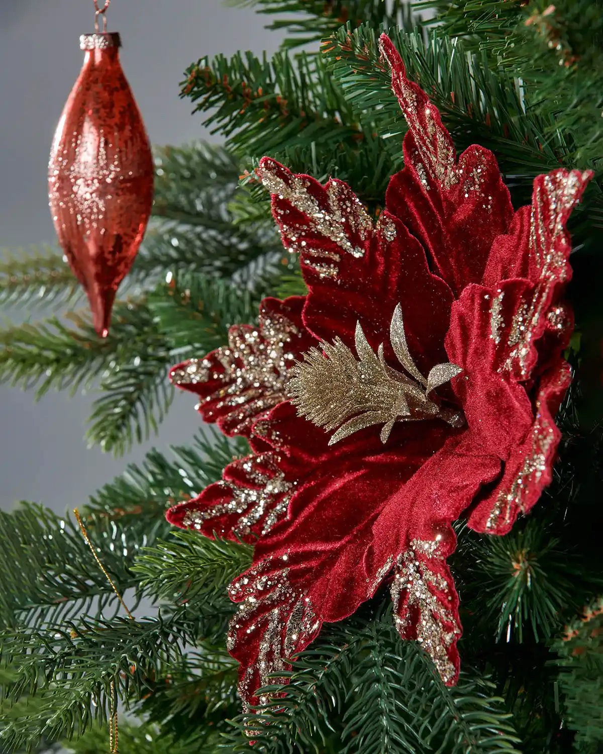 Red and gold poinsettia flower with gold accents on a Christmas tree