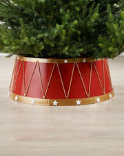 Red and gold tree skirt with star decorations under a Christmas tree on a wooden floor.