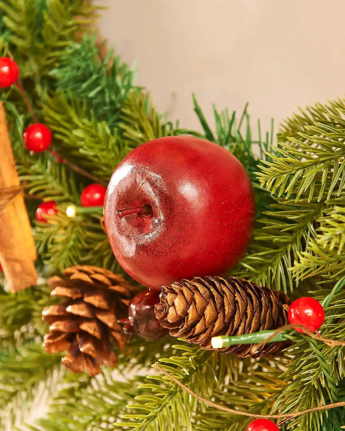 Red apple, pine cones, and red berries on a green leafy background
