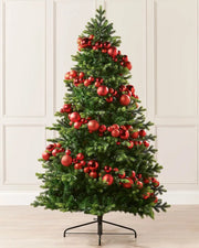 Red bauble garland wrapped around a Christmas tree against a cream panel wall