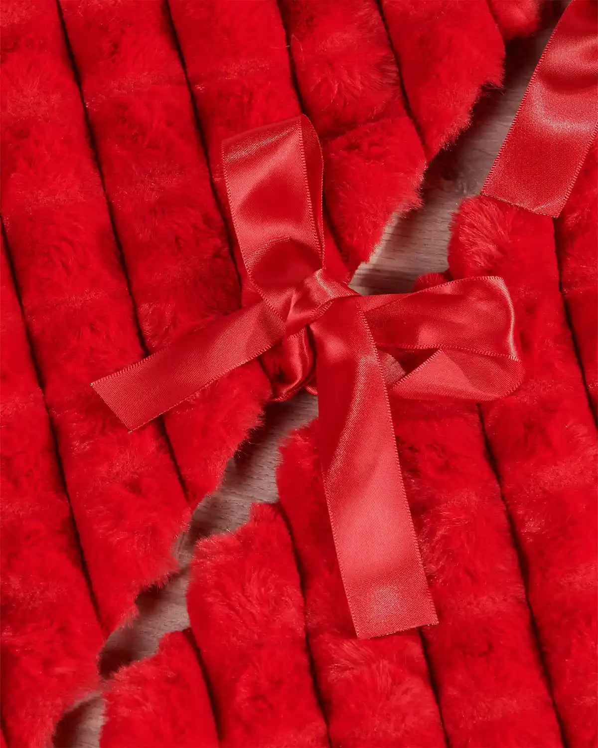 Red faux fur diamond tree skirt ribbon ties on light wooden flooring