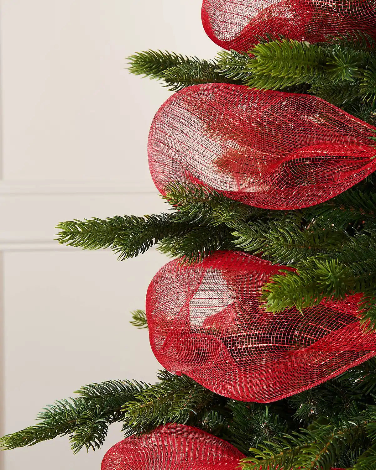 Red mesh fabric on a Christmas tree against a white wall