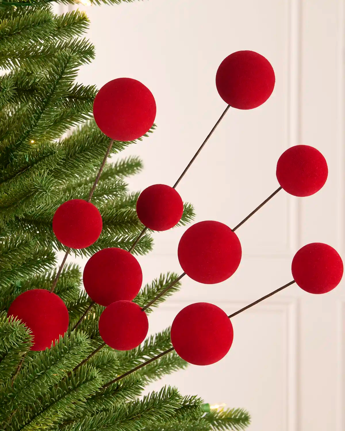 Red velvet bauble pick on a Christmas tree against a light background
