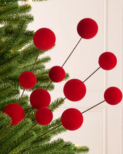Red velvet bauble pick on a Christmas tree against a light background