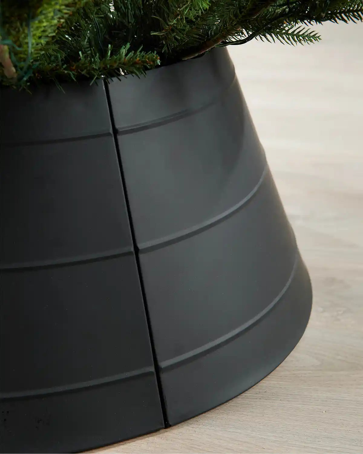 Close-up of right side of black metal tree collar on light wood flooring 
