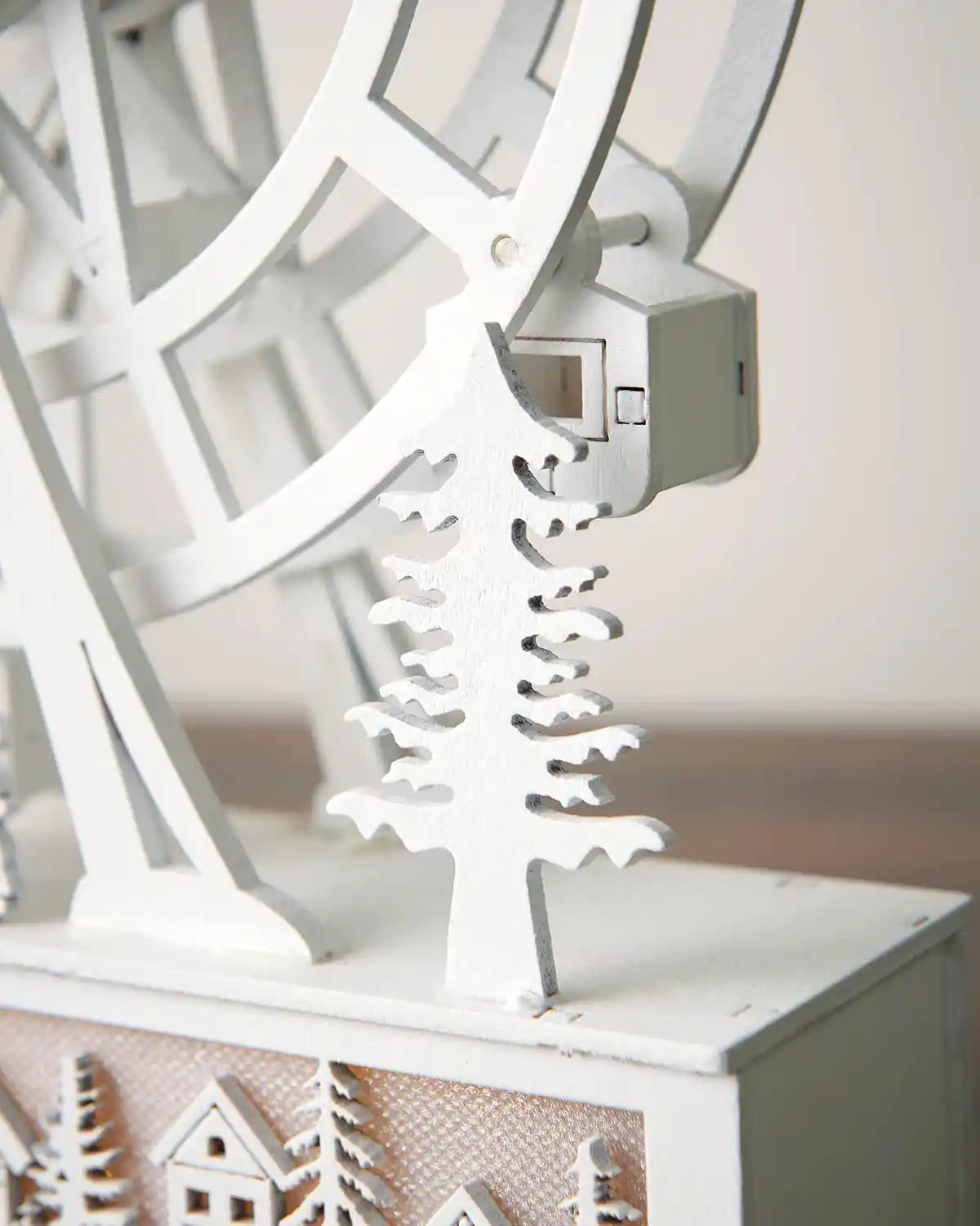 Close-up of right side of pre-lit animated white ferris wheel decoration in front of white wall