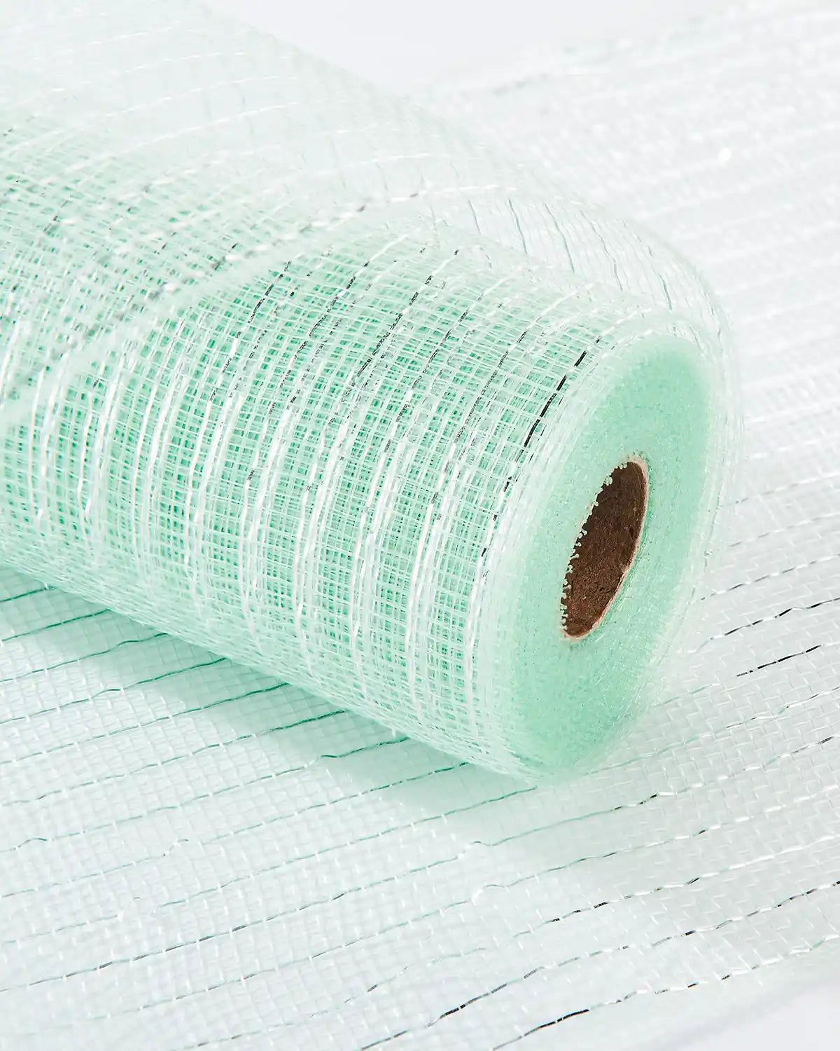 Roll of mint green mesh fabric on a white table 