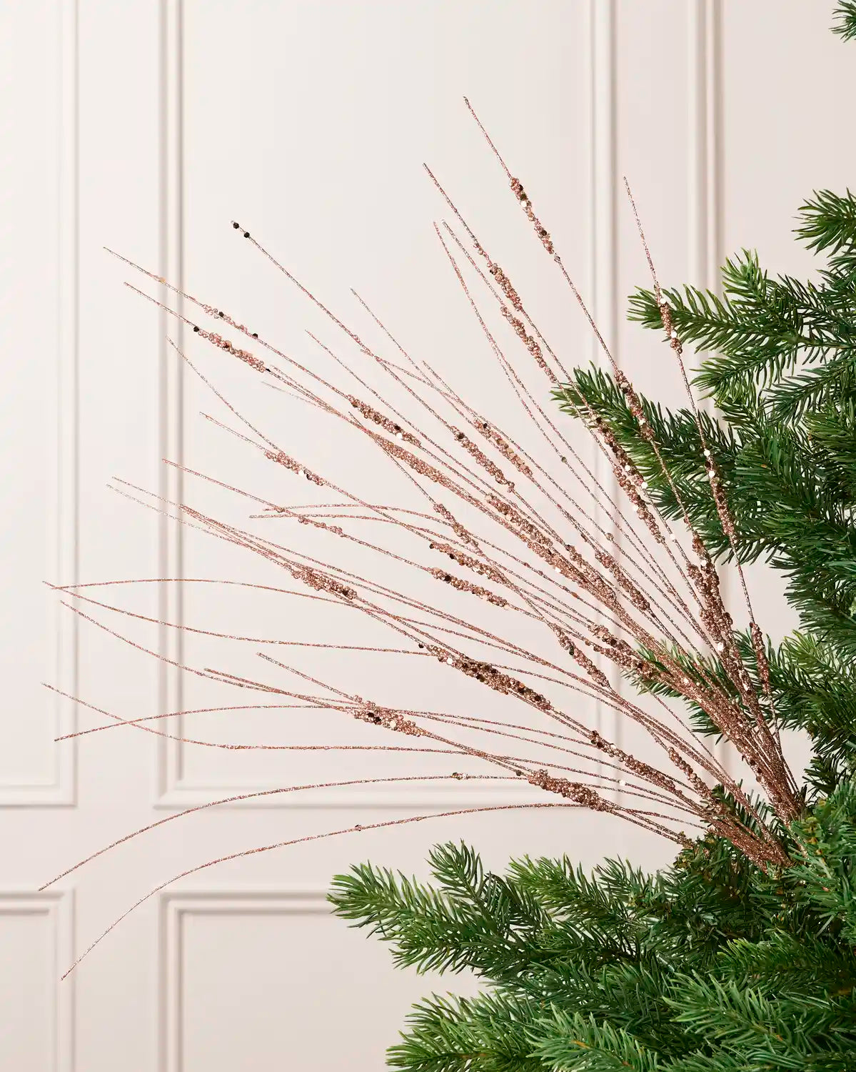 Rose Gold Glitter Wispy Spray with long, slender glitter-covered stems arranged in a fan shape on a Christmas tree
