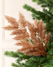 Rose Gold Large Glitter Tip Spray arranged with Christmas tree branches with a blurred cream background

