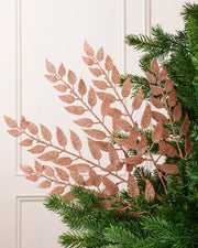 Rose Gold Leaf Christmas Tree Spray placed in Christmas tree branches with cream background
