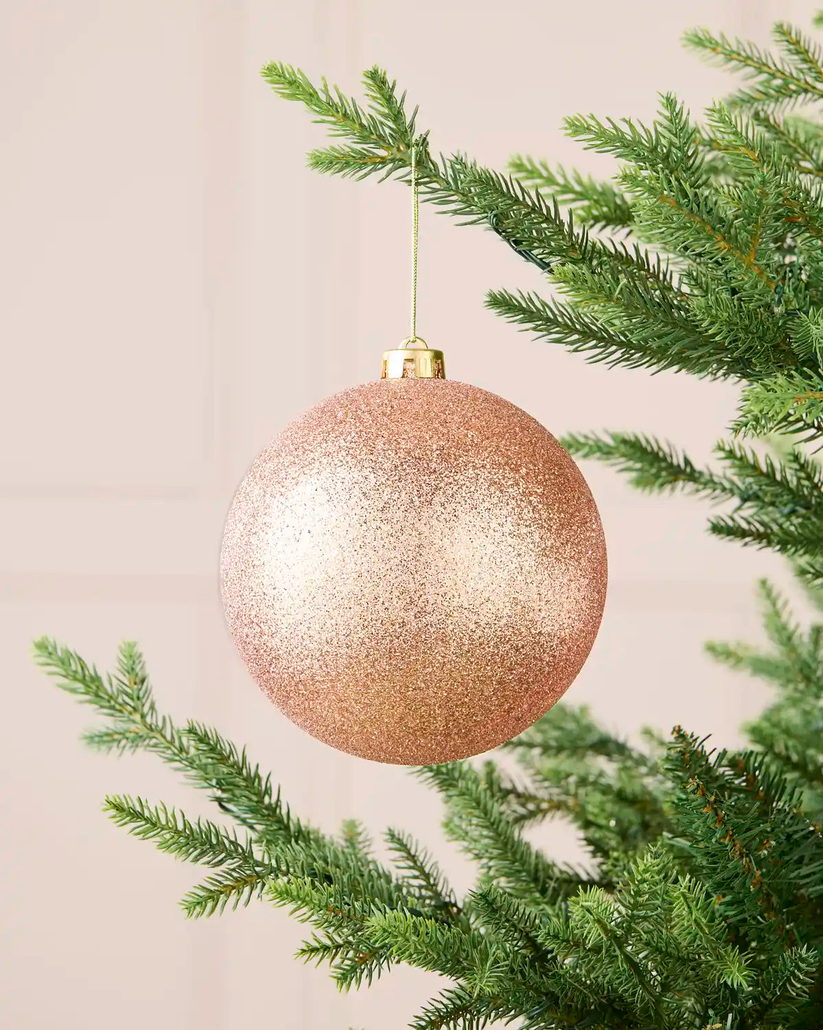Rose gold oversized glitter shatterproof bauble hanging on a Christmas tree, 15 cm