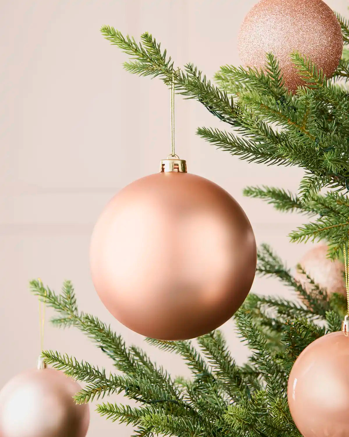 Rose gold oversized matt shatterproof bauble on a Christmas tree with coordinating baubles, 15 cm