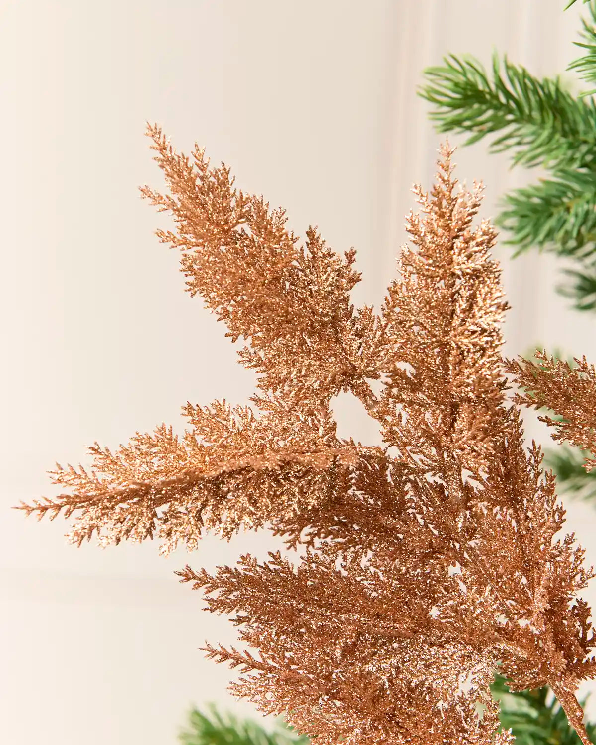 Rose gold Foliage Spray, glittering rose gold foliage on branching stems, shown in close-up to highlight its textured, shimmering leaves
