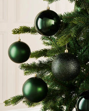 Sage Green Christmas ornaments on a tree with a white wall background