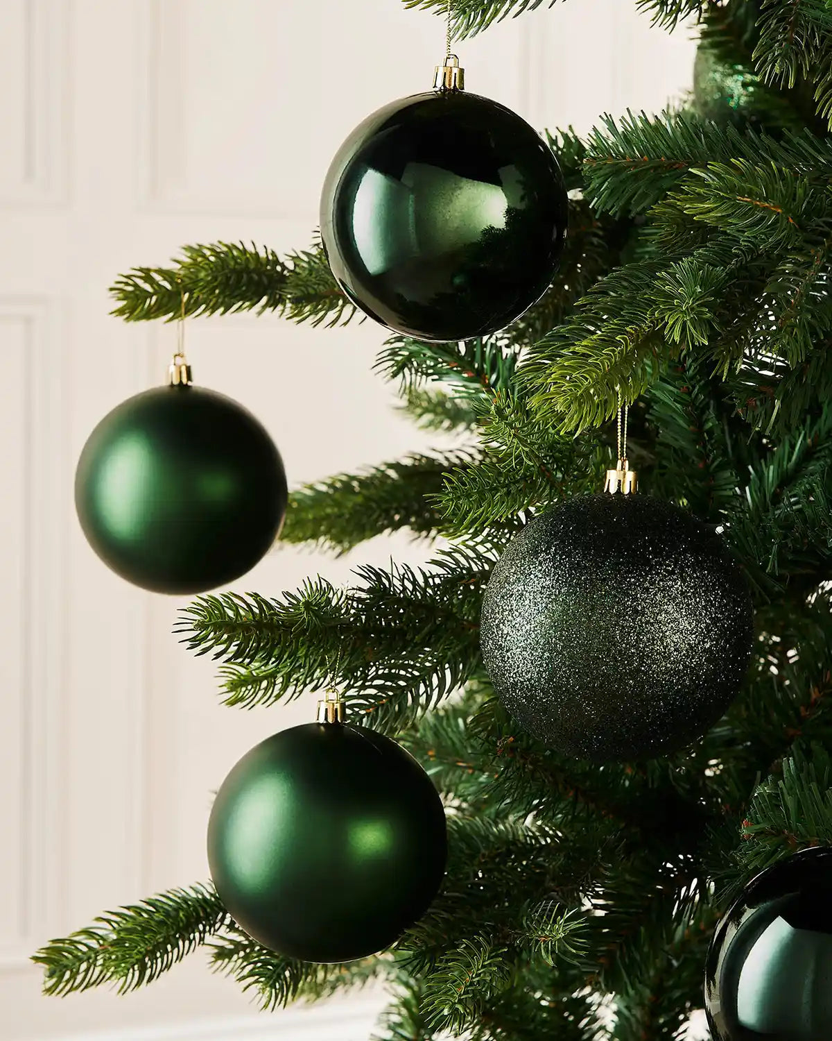 Sage Green Christmas ornaments on a tree with a white wall background