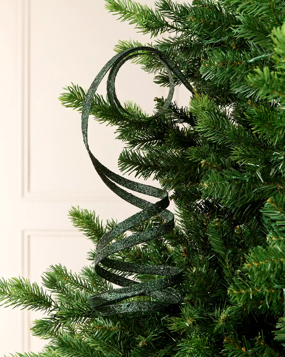 Sage Green Glitter Spiral Swirl Pick hanging from Christmas tree branch with cream background
