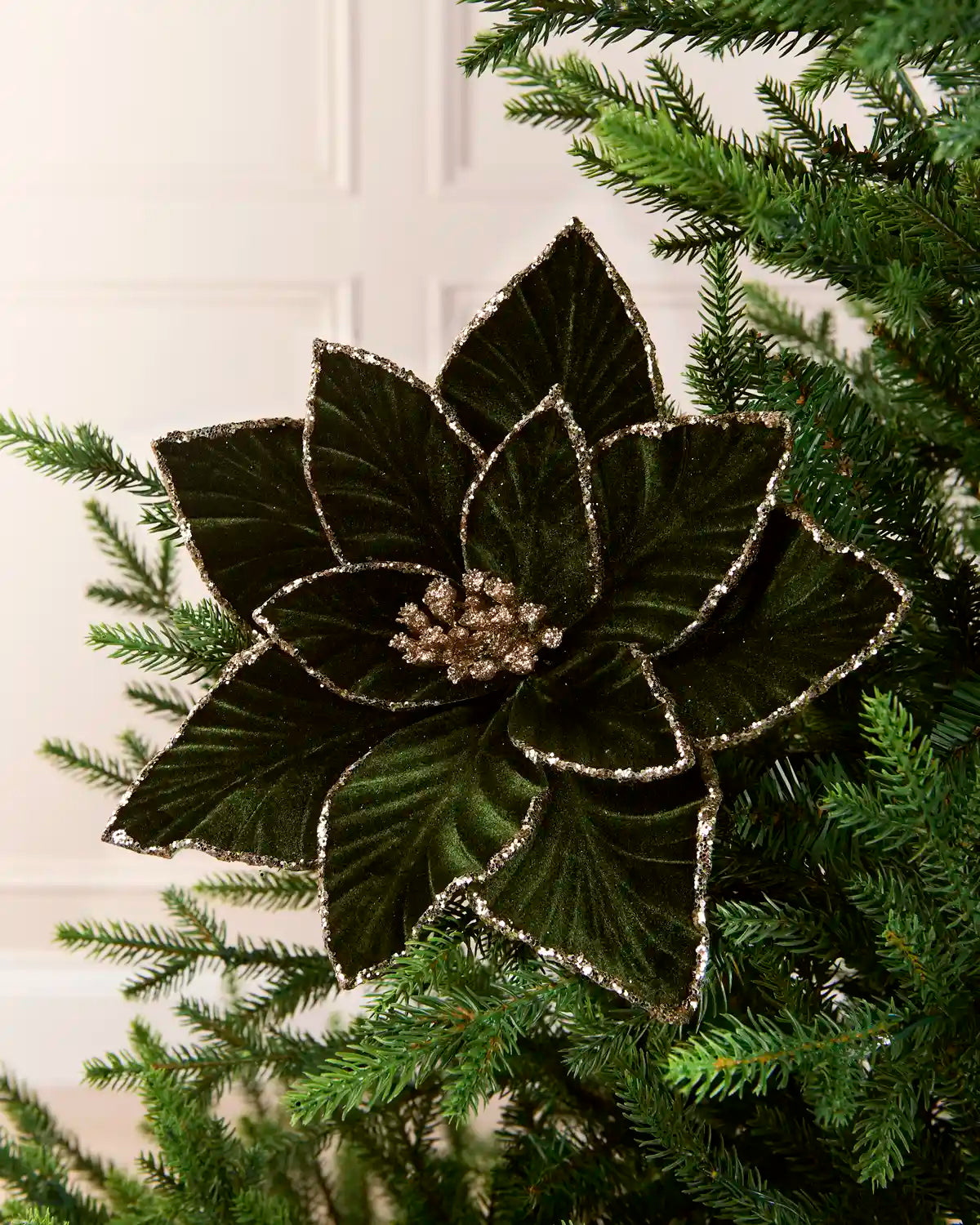 Sage Green oversized velvet artificial poinsettia displayed on a Christmas tree, featuring layered velvet petals with glittered edges and a sparkling center
