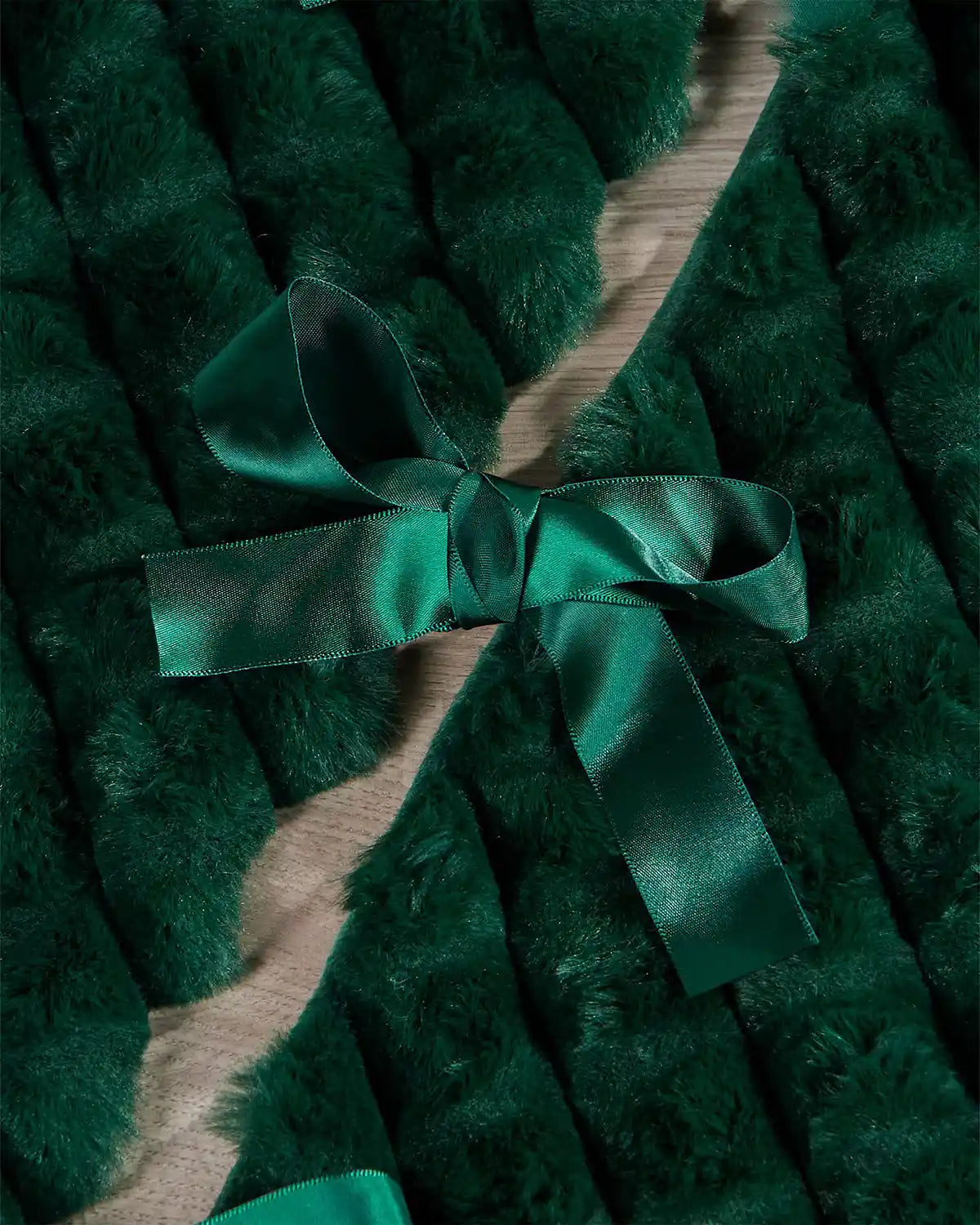 Close-up of sage green faux fur diamond tree skirt ribbon ties on light wooden flooring