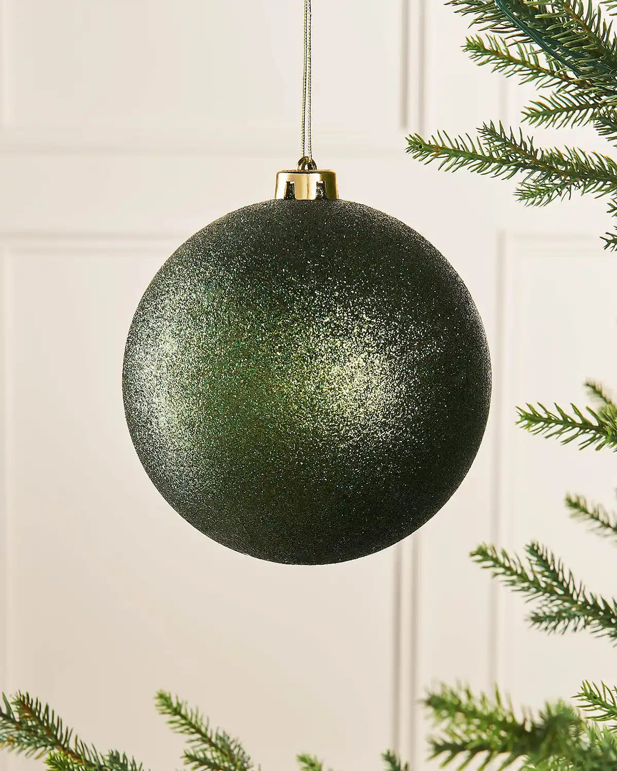 Sage green glitter oversized 15cm bauble on a Christmas tree branch
