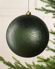 Sage green glitter oversized bauble on a Christmas tree branch