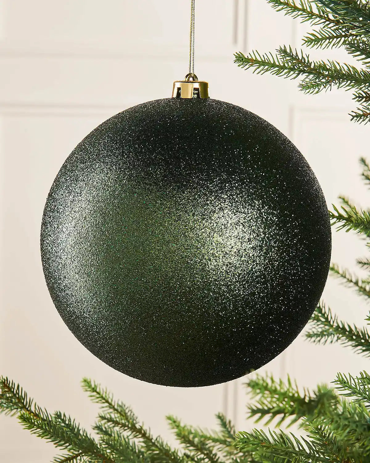 Sage green glitter oversized bauble on a Christmas tree branch