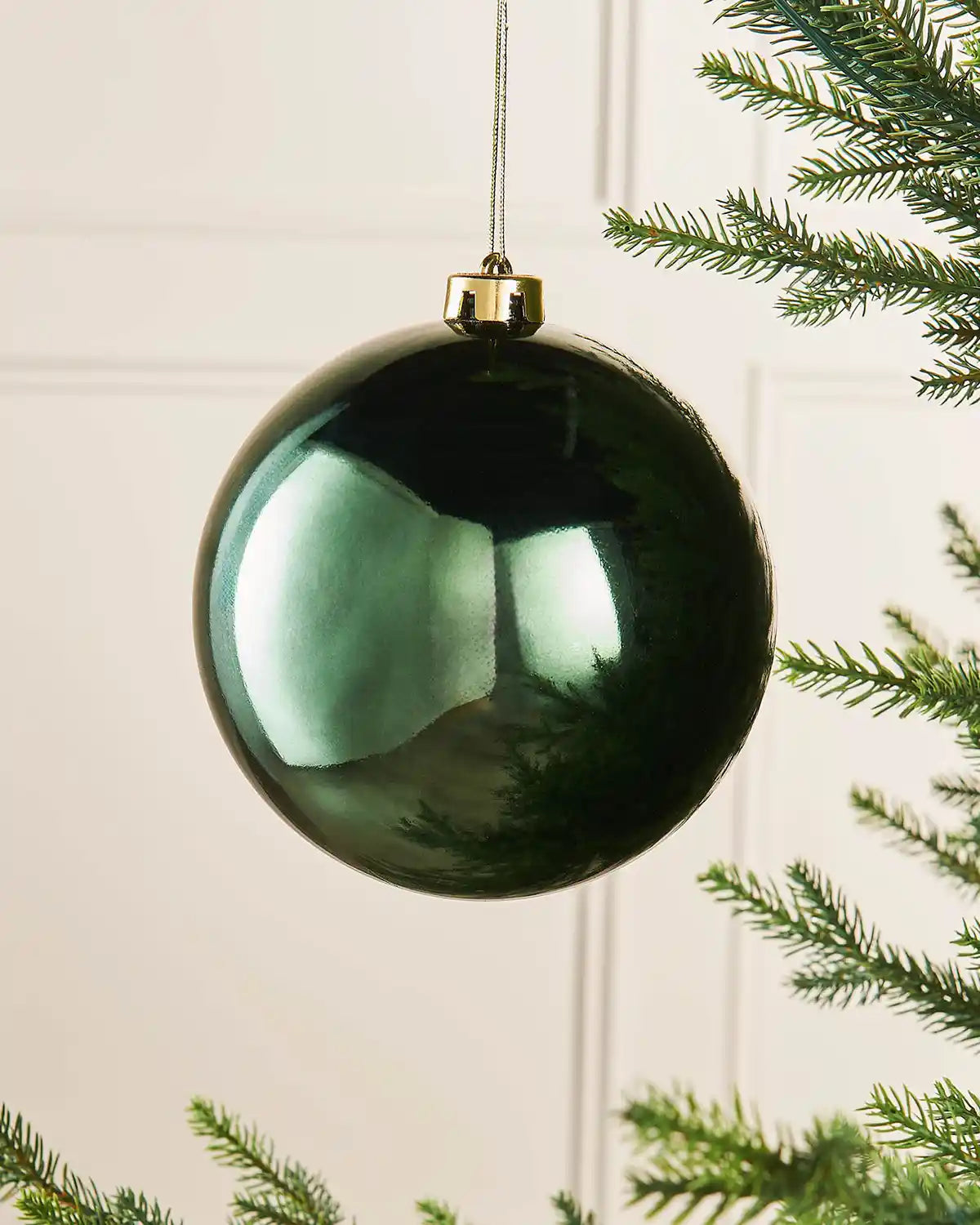 Sage green gloss oversized 15cm bauble on a Christmas tree branch