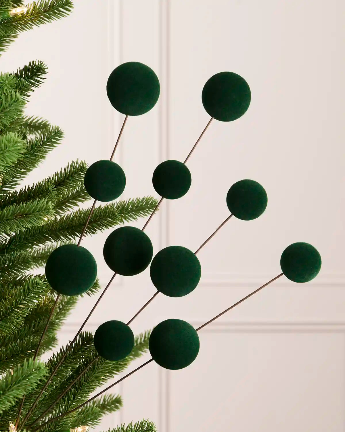 Sage green velvet bauble pick on a Christmas tree against a light background 