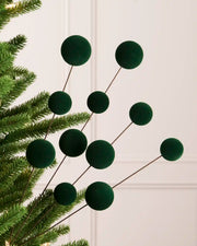 Sage green velvet bauble pick on a Christmas tree against a light background 