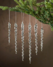 Set of 6 melting Icicle ornaments hanging on a Christmas tree with a brown background