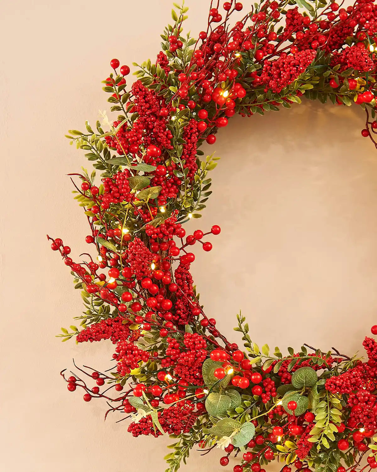Side view Decorative wreath with red berries and green leaves on a plain background