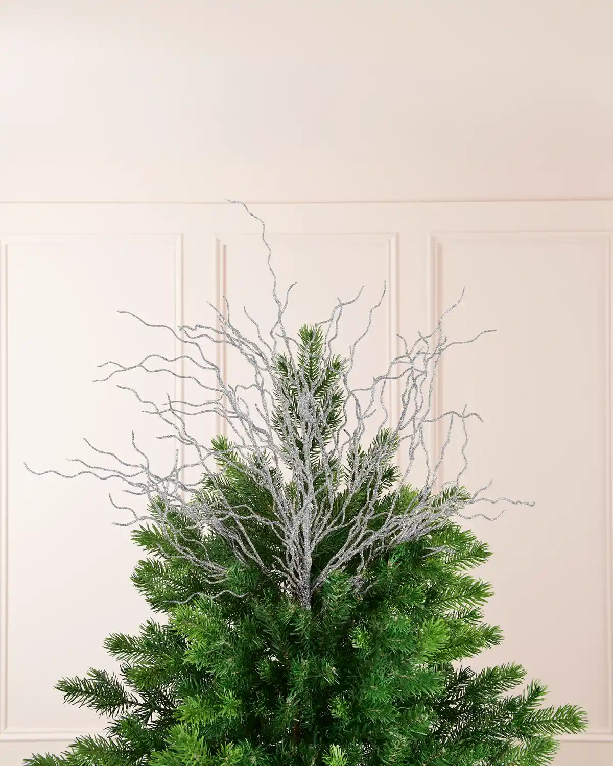 Silver 90 cm glitter twig tree topper arranged at the top of a Christmas tree.
