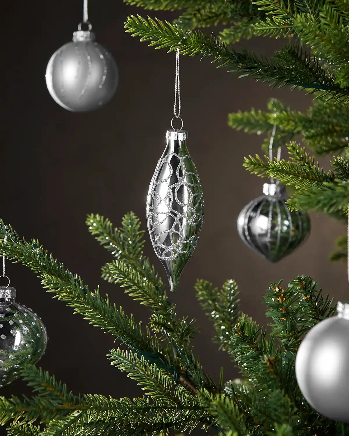 Silver Christmas baubles hanging on a tree with a dark background