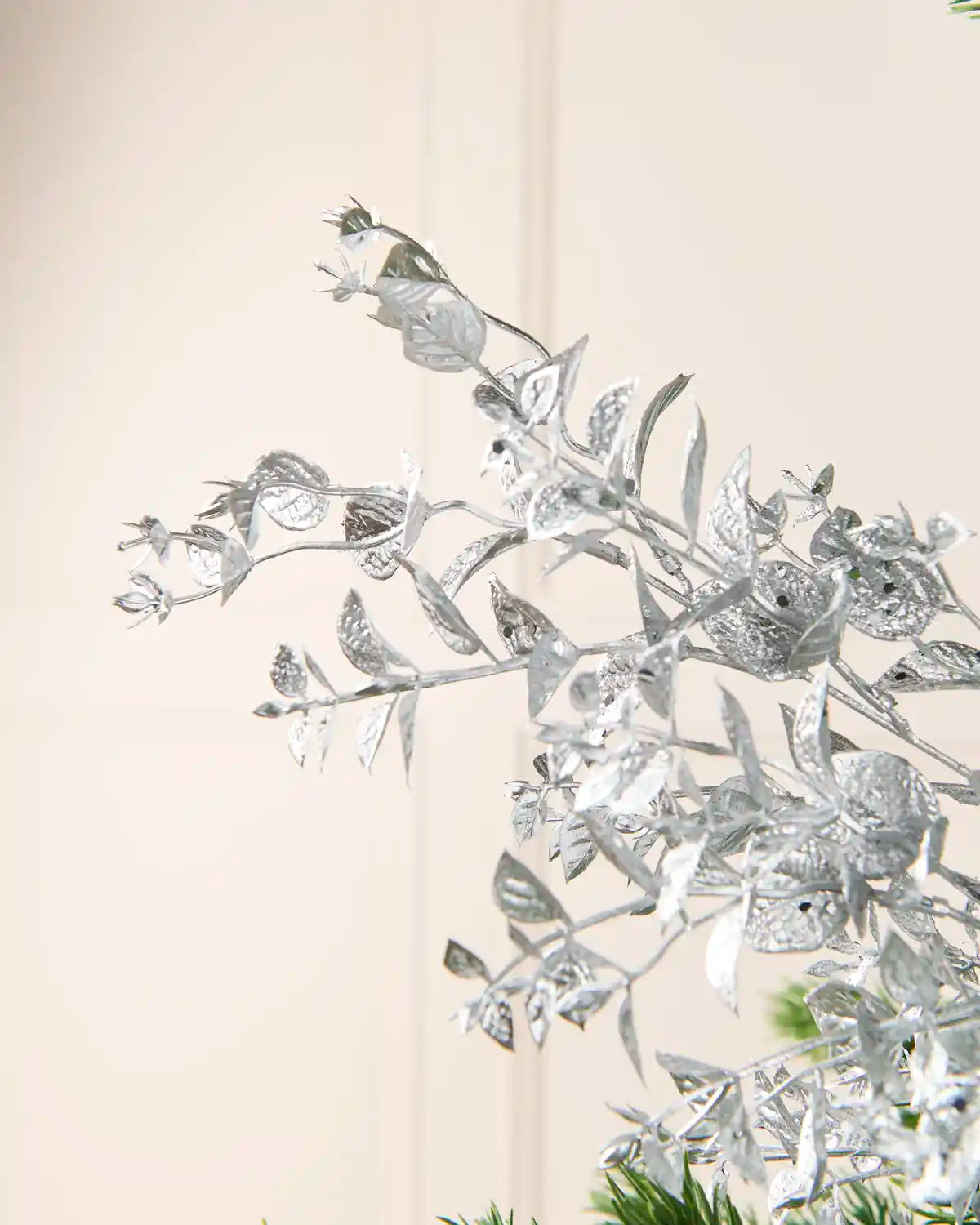 Silver Foliage Spray displayed among Christmas Tree branches, highlighting its layered Silver leaves and decorative stems.