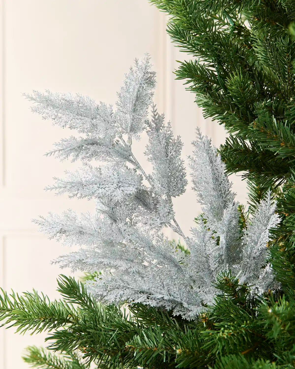 Silver Large Glitter Tip Spray arranged with Christmas tree branches with a blurred cream background
