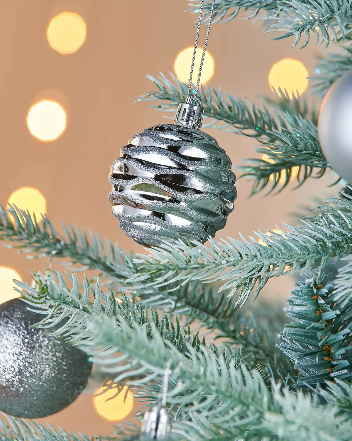 Silver bauble on a Christmas tree with blurred lights in the background