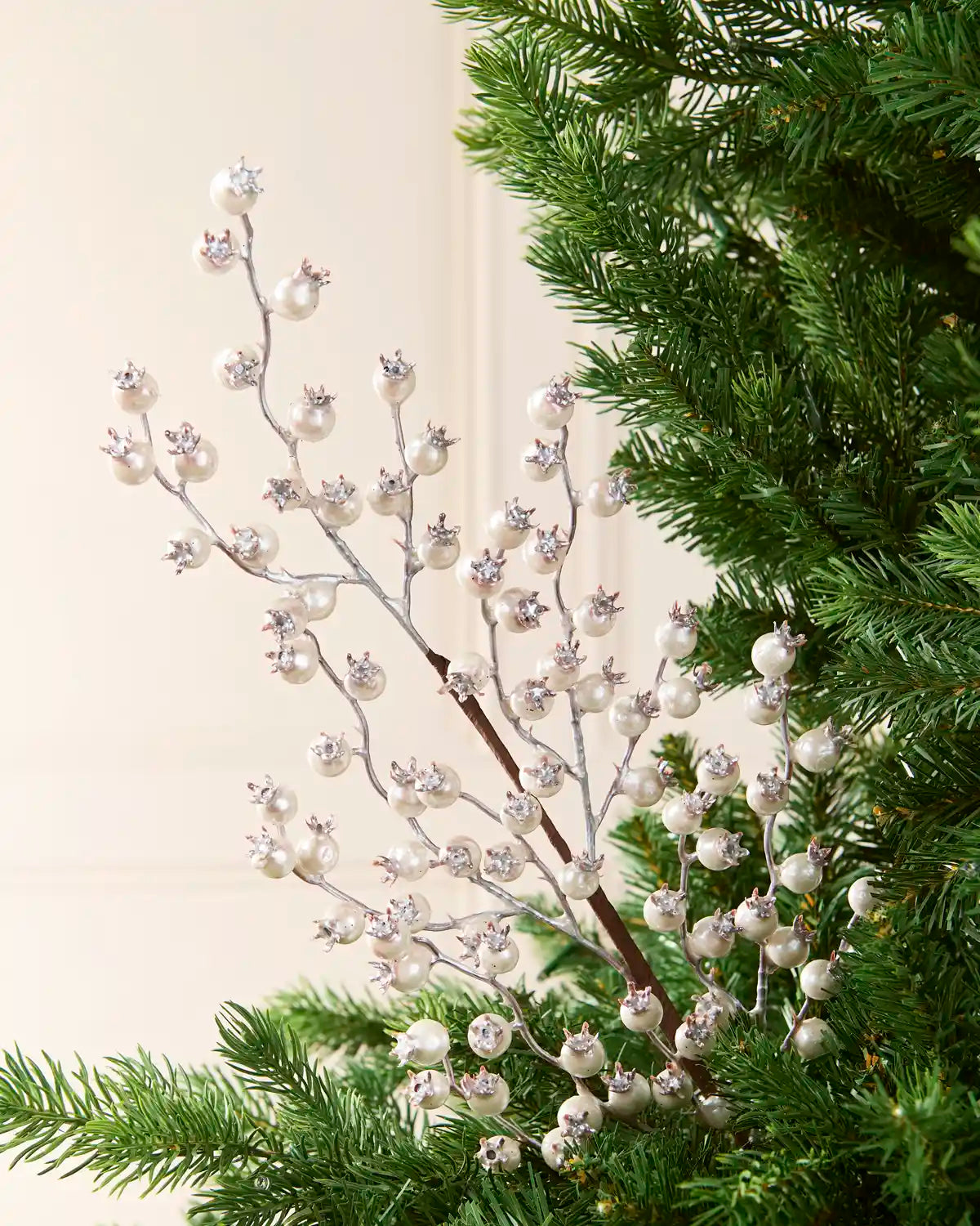 Silver berry pick, tree topper with white faux pearls and silver crystal accents, shown nestled in green pine tree branches.