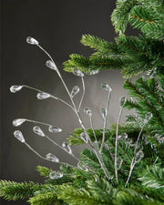 Silver crystal teardrop spray attached to Christmas tree in front of grey wall background